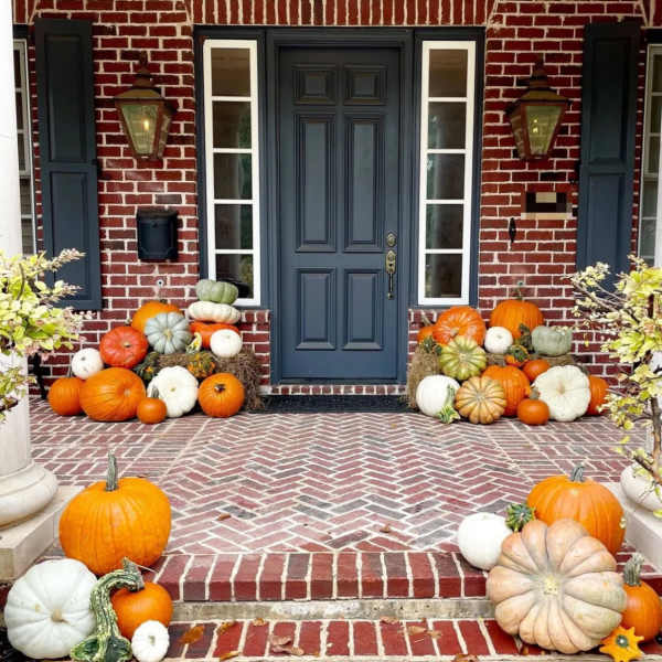 Front porch decorated with pumpkins and gourds around a blue door