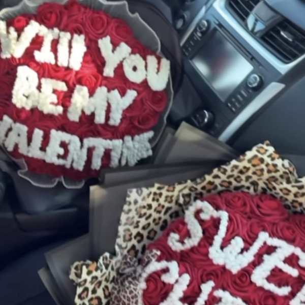 Two red rose bouquets with white lettered flowers in a car