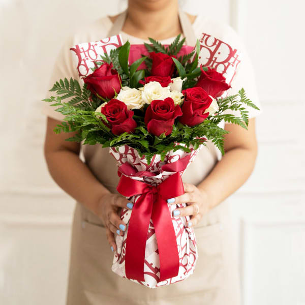 Bouquet of red and white roses wrapped in patterned paper with a red ribbon