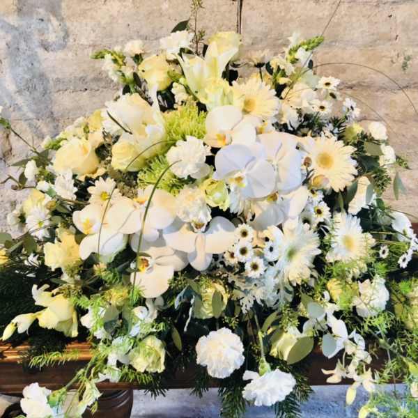 Large white floral arrangement with orchids and daisies on a table