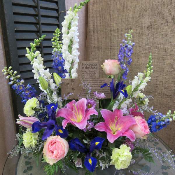Pink lilies and roses with blue and white flowers in a low arrangement