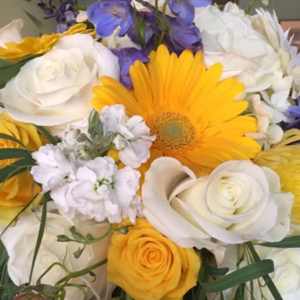 Bouquet of yellow, white, and purple flowers with a large yellow daisy
