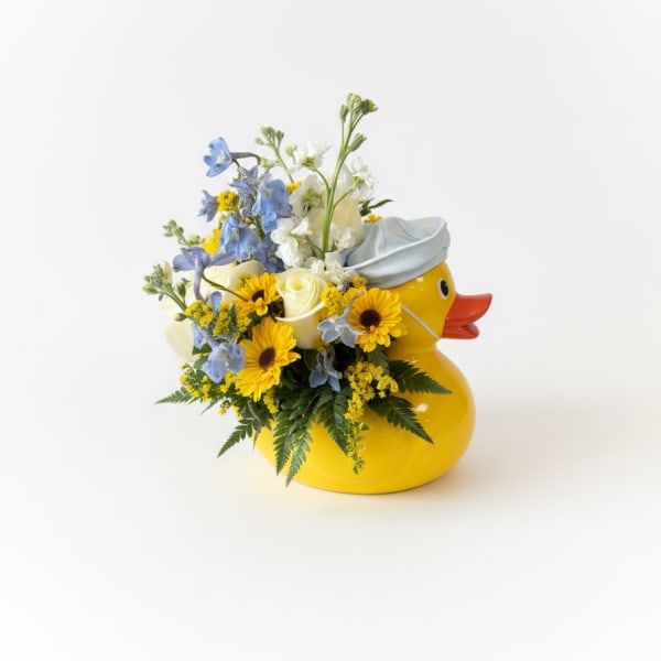 Yellow duck-shaped container holding blue, white, and yellow flowers