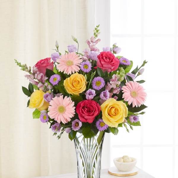 Bouquet of pink, yellow, and purple flowers in a clear glass vase
