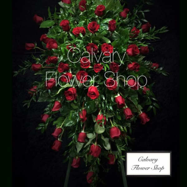Standing spray of red roses with greenery on a black background