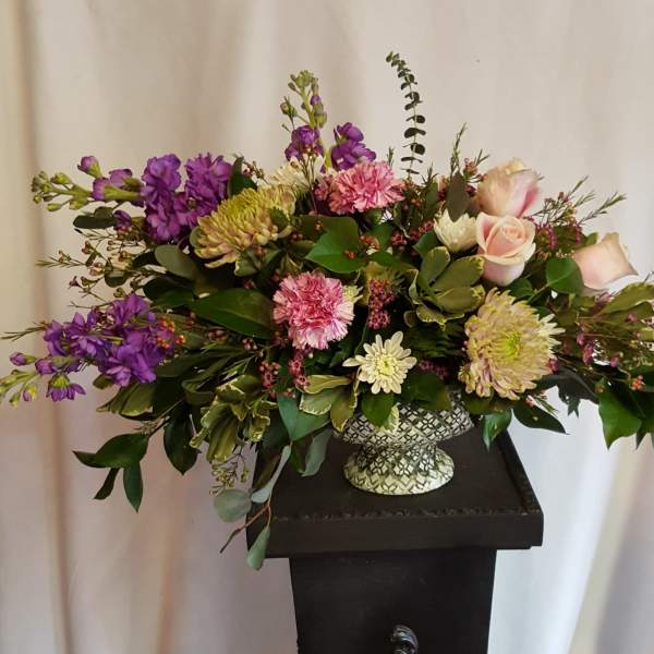 Mixed bouquet in a patterned vase with purple, pink, and cream flowers
