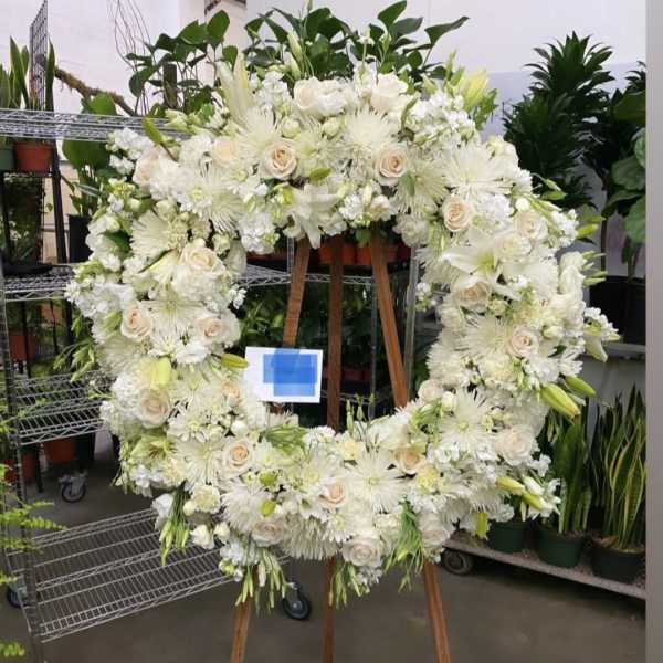 Large white floral wreath on a wooden easel