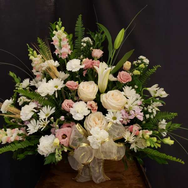 Large pastel floral arrangement with roses, lilies, and daisies in a basket
