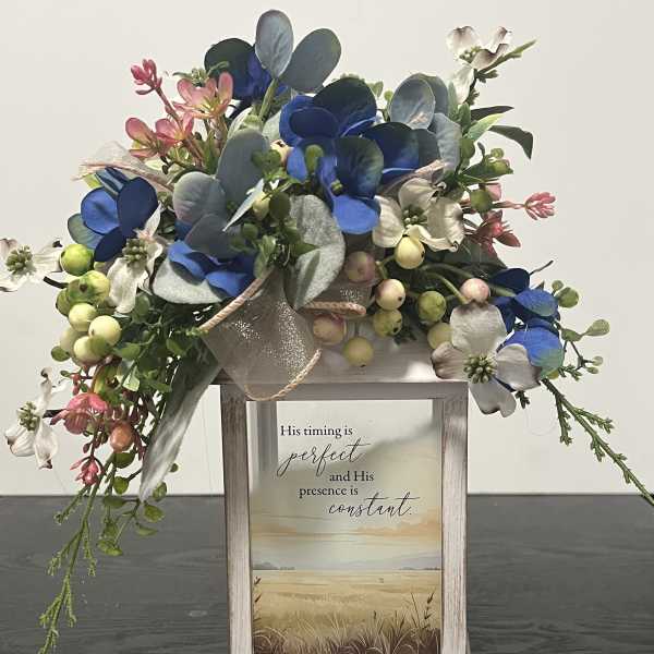 Floral arrangement with blue and white blooms in a rustic wooden frame sign
