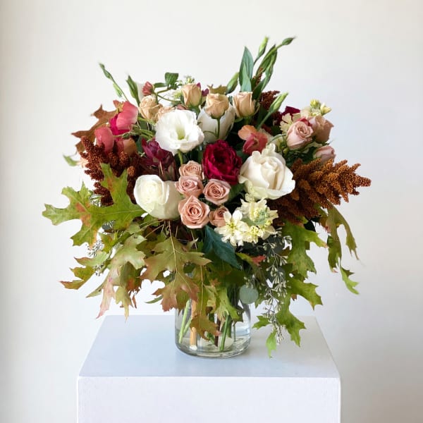 Mixed bouquet of roses and white blooms in a glass vase