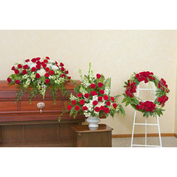 Red rose funeral arrangements with white flowers on a casket and wreath
