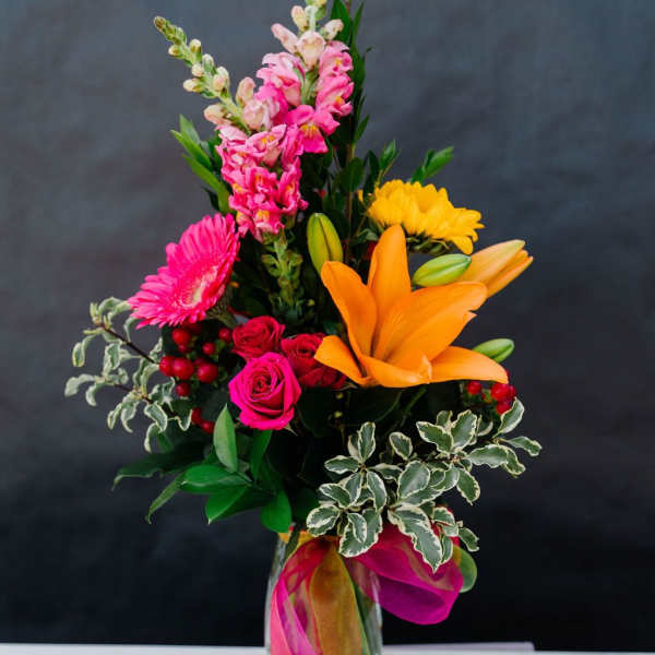 Bright mixed bouquet in a glass vase with pink, orange, and yellow flowers