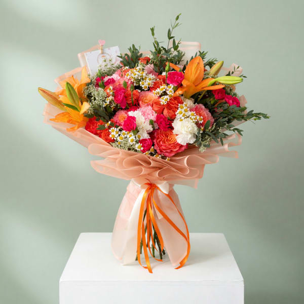 Large bouquet of orange lilies, pink roses, and white daisies wrapped in peach paper
