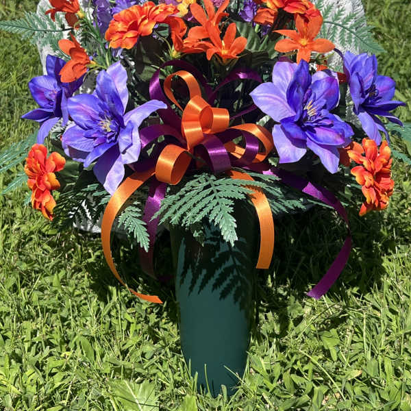 Colorful bouquet of purple and orange flowers in a green vase with ribbon
