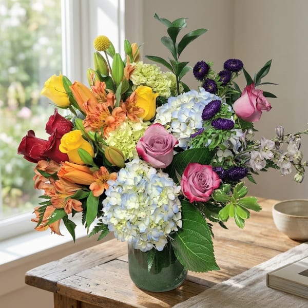 Mixed bouquet of roses, hydrangeas, and alstroemeria in a glass vase