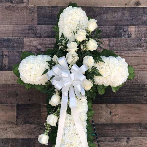 White floral cross with roses and ribbon on an easel