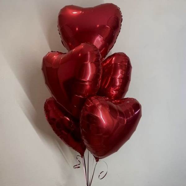 Cluster of red heart-shaped balloons tied with ribbon