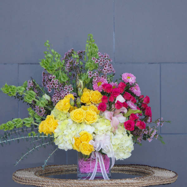 Mixed bouquet of yellow and pink flowers in a glass vase