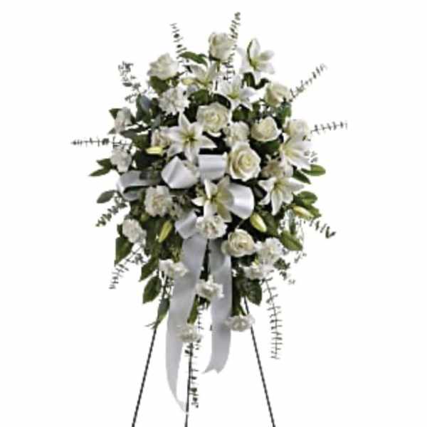 White floral standing spray on an easel with a ribbon