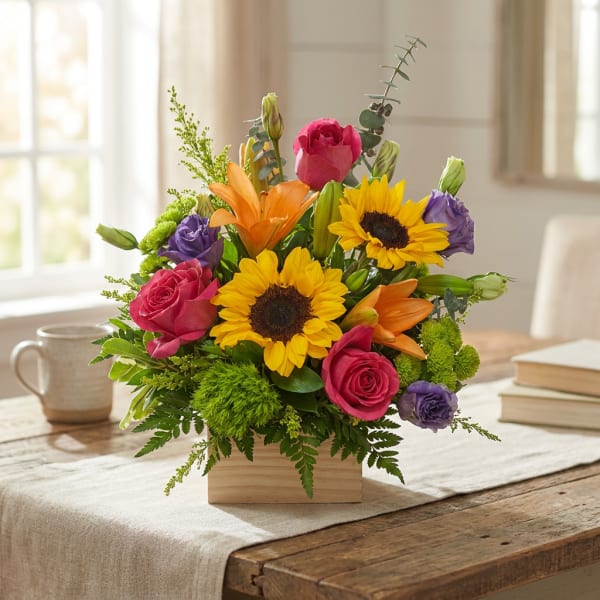 Mixed bouquet with sunflowers, roses, lilies, and purple blooms in a wooden box