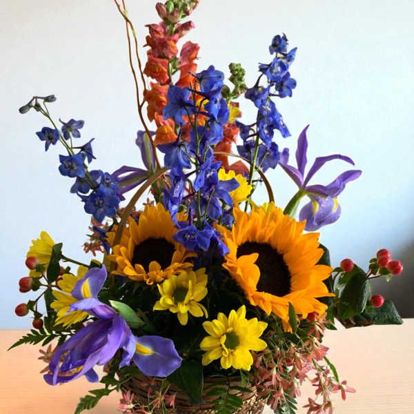 Basket arrangement with sunflowers, blue flowers, and purple irises