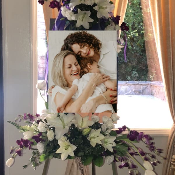 Standing floral easel with white lilies and purple orchids around a photo