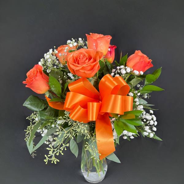 Orange rose bouquet in a clear glass vase with an orange ribbon