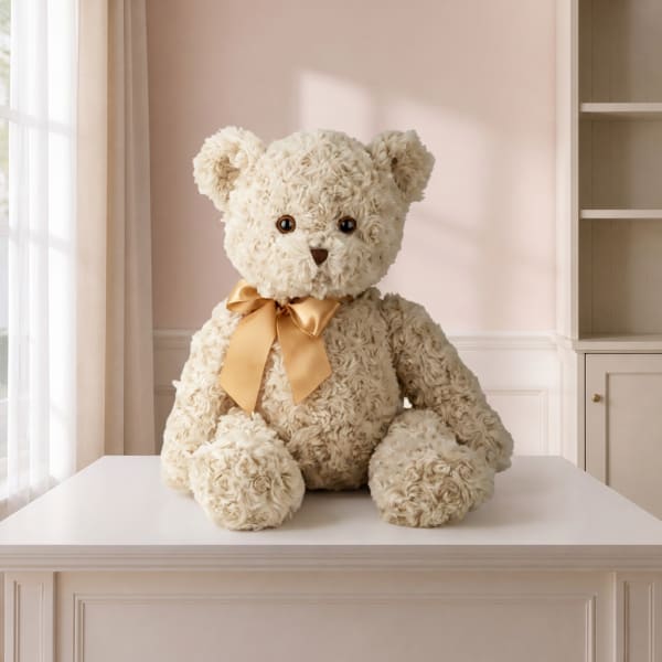 Cream teddy bear with a gold ribbon sitting on a table