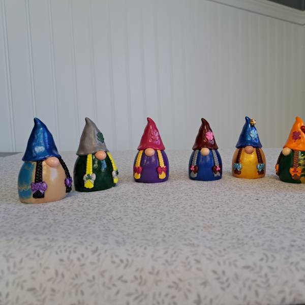 Seven small painted gnome figurines lined up on a tabletop