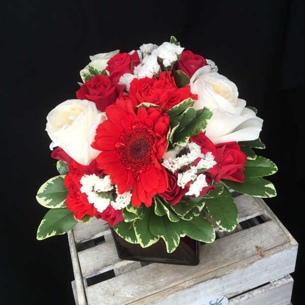 Red and white rose bouquet with a red gerbera daisy in a black vase
