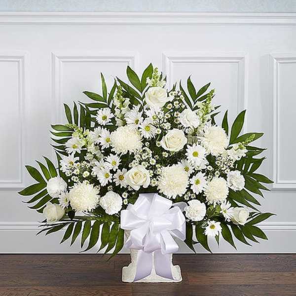 White floral standing spray with a large bow on a pedestal base