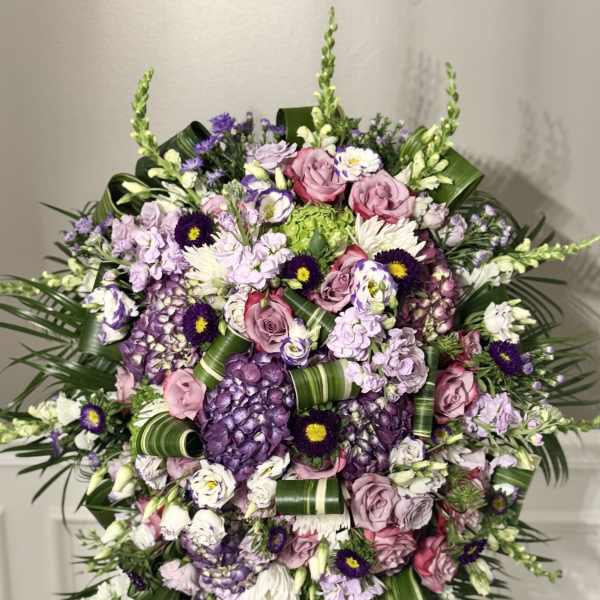 Large standing floral spray with pink and purple flowers on a black easel