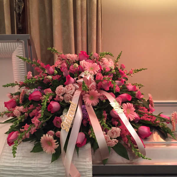 Large pink floral casket spray with ribbon streamers