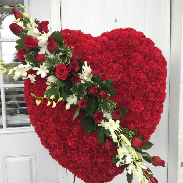 Heart-shaped red floral tribute with a diagonal spray of red roses and white orchids