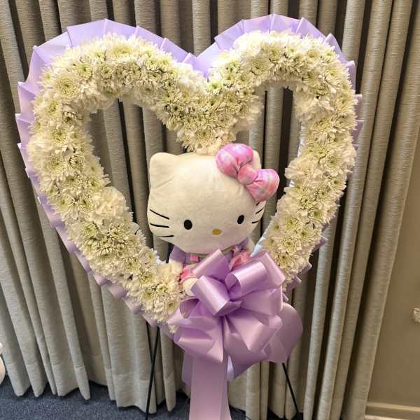 Heart-shaped white chrysanthemum wreath with a Hello Kitty plush and lavender bow