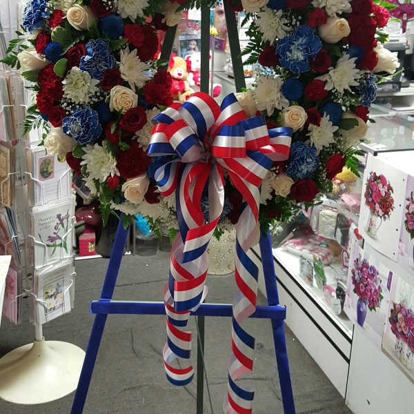 Large floral wreath with red, white, and blue flowers on an easel
