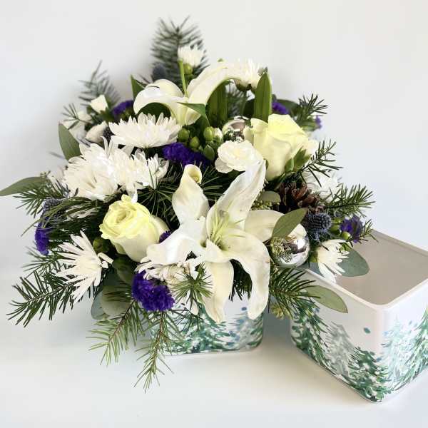 White lilies and roses in a decorative tin container
