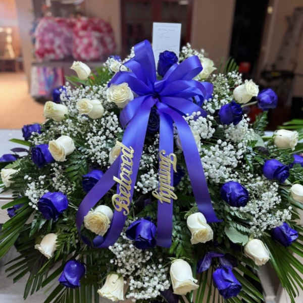 Large wreath of white and blue roses with a purple ribbon bow