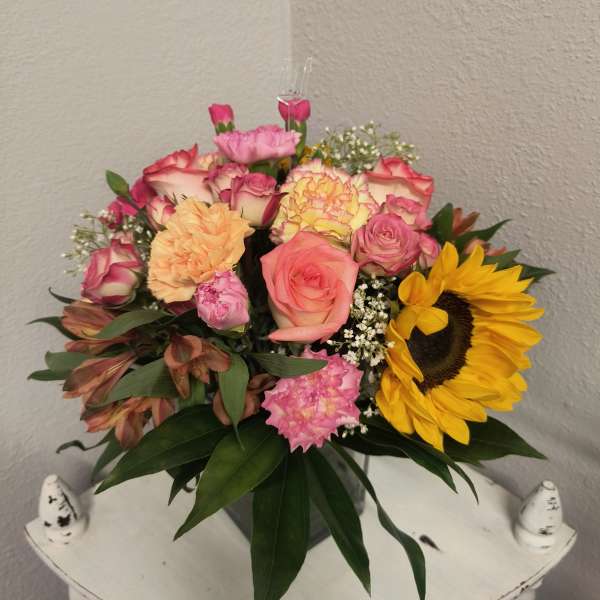 Mixed bouquet of roses, carnations, and a sunflower in a vase