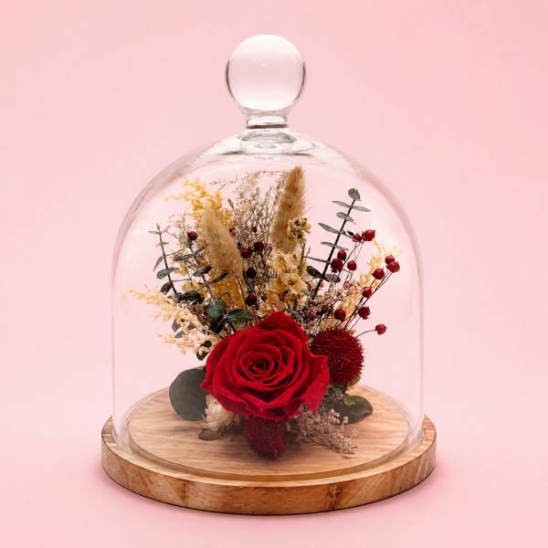 Red rose arrangement under a glass dome on a wooden base