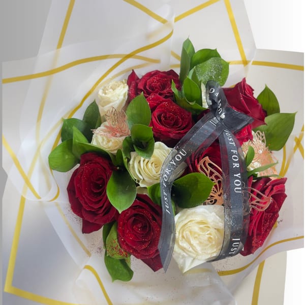 Bouquet of red and white roses wrapped in white paper with a black ribbon