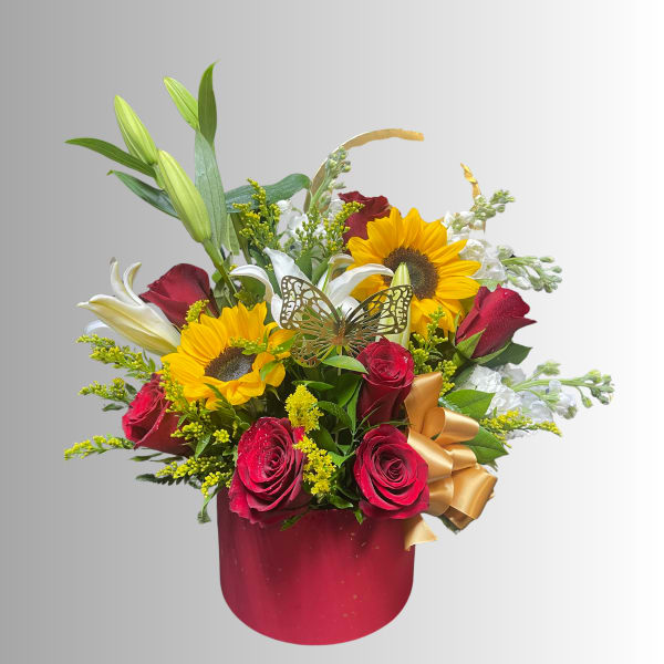 Bouquet of red roses, sunflowers, and white lilies in a red box with a gold bow