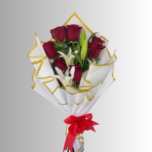Bouquet of red roses and white lilies wrapped in white paper with gold trim