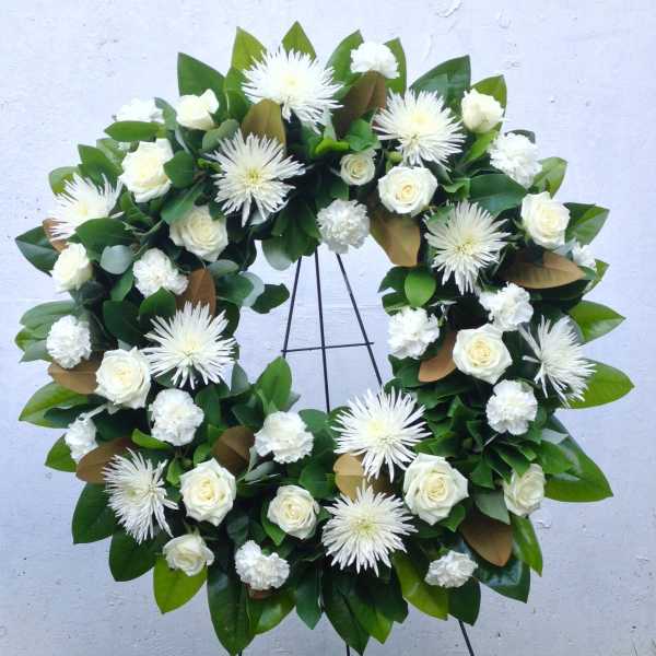 White rose and chrysanthemum wreath on a black stand