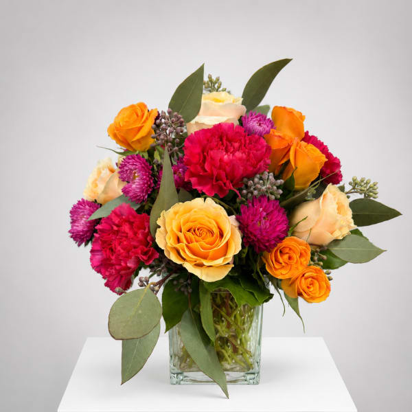 Mixed bouquet of orange and pink flowers in a glass vase