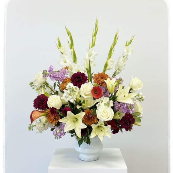 Mixed floral arrangement in a white vase with tall white spikes
