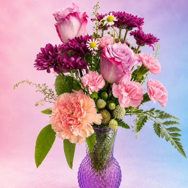 Pink and purple mixed bouquet in a purple glass vase
