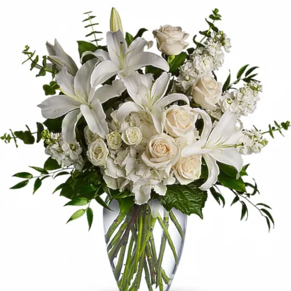 White lilies and roses arranged in a clear glass vase