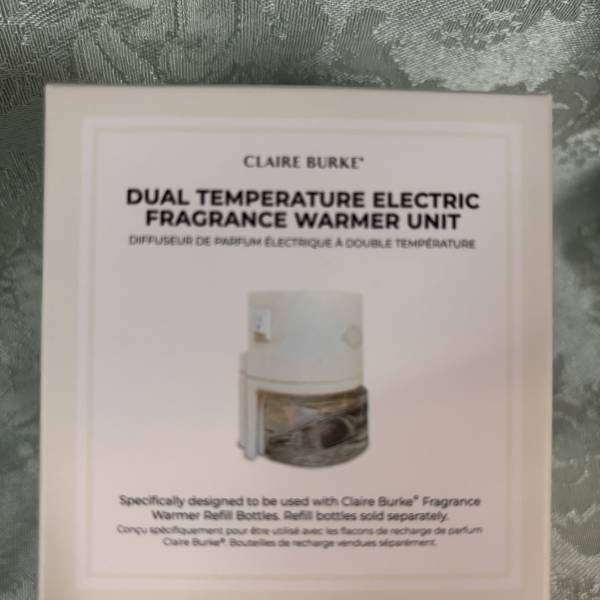 Boxed Claire Burke electric fragrance warmer unit on patterned fabric