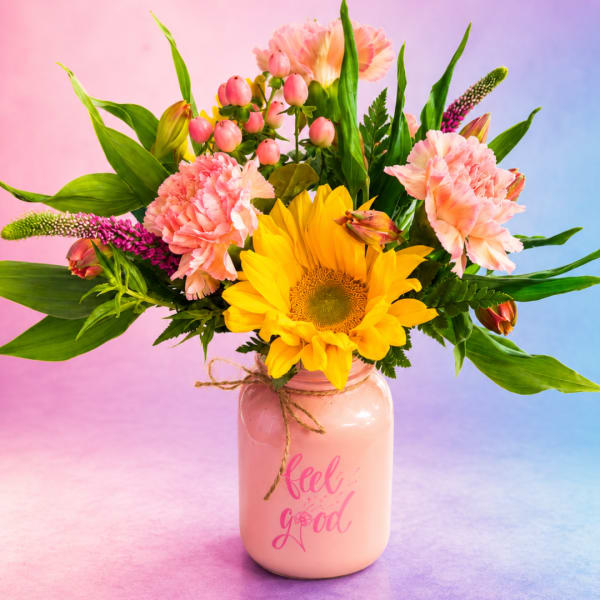 Sunflower and pink carnation bouquet in a pink mason jar vase